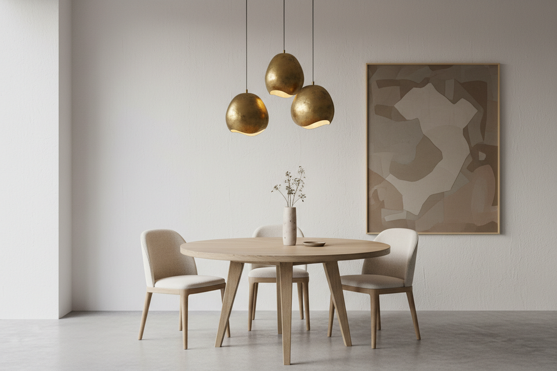 Cluster of three aged brass pendant lights over a round oak dining table — warm 2700K light, Nordic modern interior | RModern pendant lighting guide